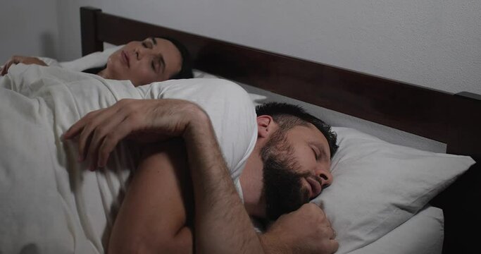 Close up  of caucasian couple restfully sleeping up in bed with white linens in light room.Man amd woman having restful sleep and insomnia 4k 