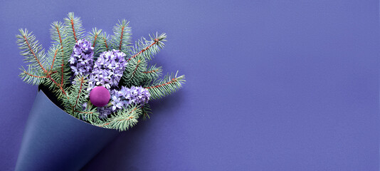 Winterpanoramabanner mit Blumenstrauß auf lila sehr peri-monochromem Papierhintergrund. Tannenzweige und blaue Hyazinthenblüten. Einfache minimale Weinzeitanordnung. Flache Lage, Ansicht von oben.