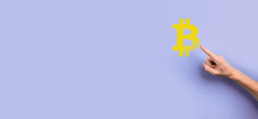 Male hand holding a bitcoin icon on blue background. Bitcoin Cryptocurrency Digital Bit Coin BTC Currency Technology Business Internet Concept.