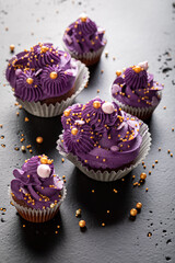 Delicious cupcakes with golden sprinkles and violet whipped cream.