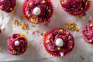 Fototapeta na wymiar Unique red cupcakes with golden sprinkles and cream.