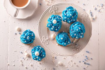 Homemade blue cupcakes served with coffee in white porcelain.