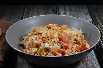 Fried rice noodle with chopped crab stick dressing with special sauce serving on the plate. Famous street food menu in Korea restaurant. 