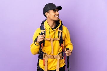 African American man with backpack and trekking poles over isolated background looking side