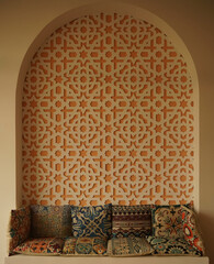 Morocco interior style. Colorful asian pillows on the couch near wall with pattern. Middle east...