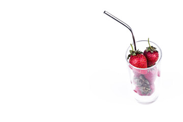 Fresh strawberry in glass cup with straw on white background. Summer refreshing juice creative concept.