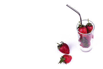 Fresh strawberry in glass cup with straw on white background. Summer refreshing juice creative concept.