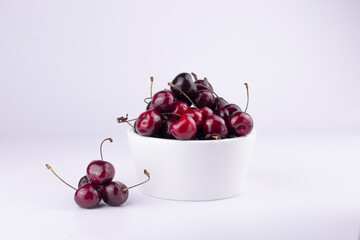 Sweet red cherry in white bowl on white background.