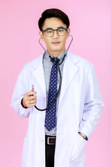 Portrait studio shot of Asian successful professional male doctor in white uniform wearing eyeglasses and stethoscope pose with successful action and confident on pink background