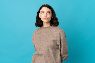 Obraz premium Teenager Ukrainian girl isolated on blue background and looking up