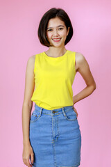 Portrait close up studio shot of Asian young pretty teenager short hair girl model in yellow sleeveless shirt stand smiling look at camera on pink background with copy space
