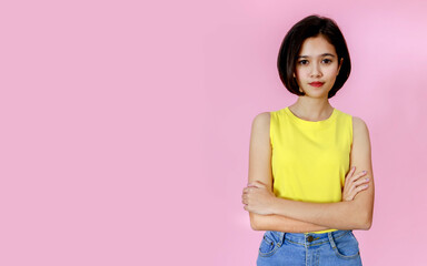 Portrait close up studio shot of Asian young pretty teenager short hair girl model in yellow sleeveless shirt stand smiling look at camera on pink background with copy space