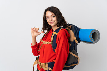 Teenager mountaineer girl with a big backpack isolated on white background proud and self-satisfied