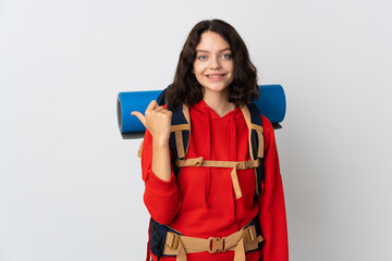 Teenager mountaineer girl with a big backpack isolated on white background pointing to the side to present a product