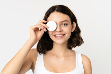 Teenager Ukrainian girl isolated on white background with cotton pad for removing makeup from her face and smiling