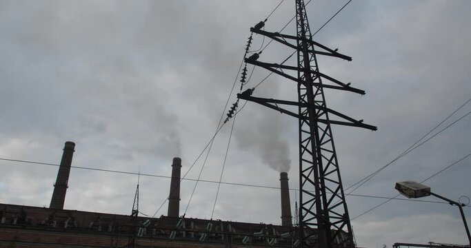 Tracking Shot Of Power Lines Of Combined Heat And Power Plant Against Dramatic Cloudy Sky. �oncept Of Global Warming, Environmental Disaster And The Use Of Unsustainable Fuels