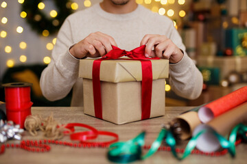 Close up of man's hand tying a bow on gift