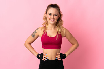 Young Brazilian woman isolated on pink background posing with arms at hip and smiling