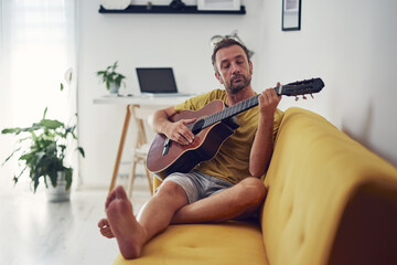 Man playing acoustic guitar at home.