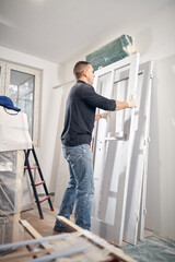 Young adult man painting on a DIY budget renovation of his new home apartment.