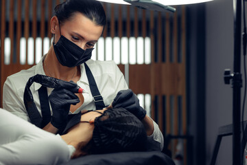 Permanent makeup tattooing of eyebrows Cosmetologist applying make up