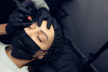 Permanent makeup tattooing of eyebrows Cosmetologist applying make up - obrazy, fototapety, plakaty