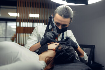 Permanent makeup tattooing of eyebrows Cosmetologist applying make up