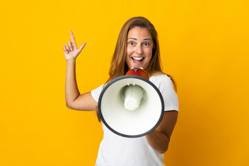 Middle age brazilian woman isolated on yellow background shouting through a megaphone and pointing...
