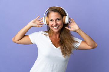 Middle age brazilian woman isolated on purple background listening music