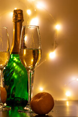 A bottle of sparkling wine, champagne glasses and tangerines, on a dark base and with a light background. Bright, joyful holiday atmosphere. Merry Christmas and Happy New Year.