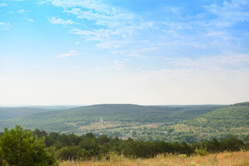 View from the mountain to the green valley with hills and forests on a summer day