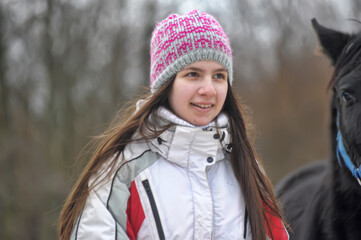 girl in winter with a horse in the paddock