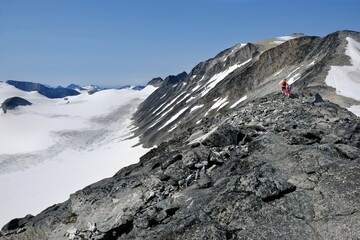 Beautiful mountain view of Jotunheimen National Park. Silhouettes of hiking people on trail to summit Galdhopiggen in little snowy conditions. Norway, 
Scandinavia