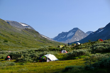 Fototapeta na wymiar Colorful tents standing in Visdalen valley, on Visa River in Jotunheimen Mountains in Norway. Jotunheimen National Park, Scandinavia