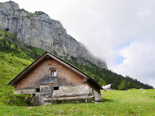 Traditional mountain hut in front of rock face. Alpstein, Switzerland.