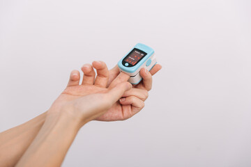 Pulse oximeter with hand of doctor isolated on white. Measuring oxygen saturation, pulse rate and oxygen levels. The concept of portable digital device to measure person's oxygen saturation.