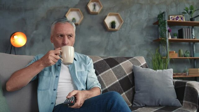Middle age man sit couch chill see comedy drink latte in modern living room