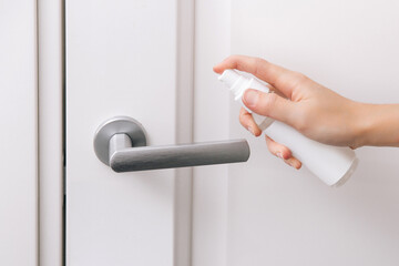 Cleaning white door handles with an antiseptic wet wipe and sanitizer spray. Disinfection in hospital and public spaces against corona virus. Woman hand using towel for cleaning home room door link. - obrazy, fototapety, plakaty