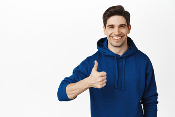 Very good. Smiling confident male model shows thumbs up and look pleased, satisfactory result,...