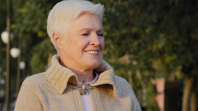 Closeup wrinkled face of 65s happy elderly woman outdoors looking aside having wide smile, dental implants and prostheses satisfied client portrait, insurance for older people, natural beauty concept