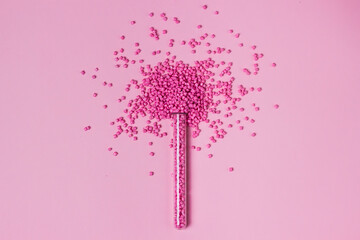 Pink granules of polypropylene or polyamide in test tube. background. Plastics and polymers...