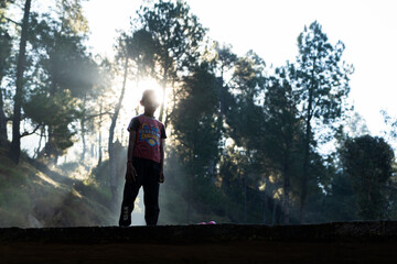 silhouette of a young boy and sun rays in the background