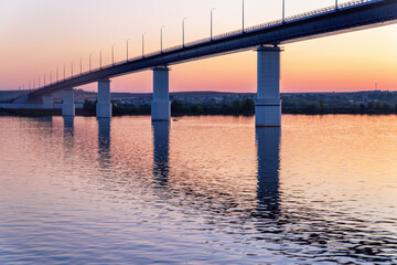 Fototapeta na wymiar Automobile bridge over the river at sunset