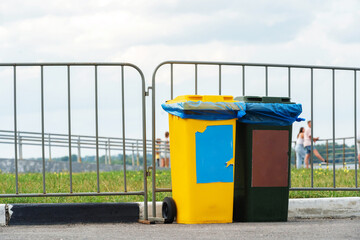 Waste bins made of plastic on the background of a metal fence. Copy space