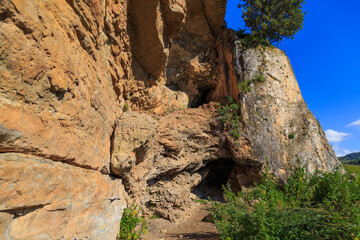 Orange rocks, small caves, a tree on top of a cliff. Grishkina Balka, Karachay-Cherkess Republic, Russia
