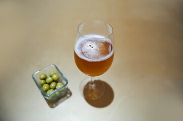 glass of lager with a bowl of olives