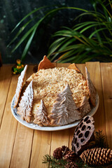 Napoleon cake decorated with Christmas gingerbread cookies. Fir branches, cones, candles, coffee, side view, wooden background.