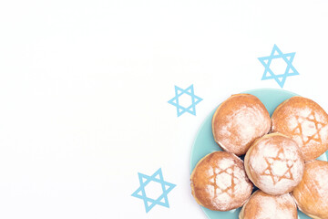 Hanukkah holiday scene with traditional Hanukkah donuts sufganiyot and blue David stars on white...