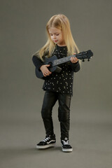 Studio portrait of adorable little girl playing ukulele	
