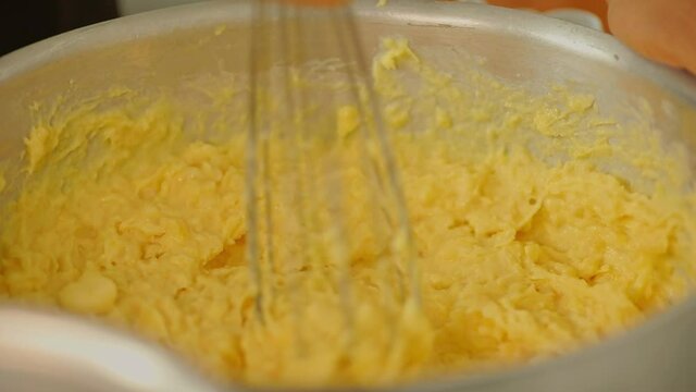 Mashing cassava in a big mixing bowl with a whisk - yuca harvested from organic farms in the Amazon rainforest